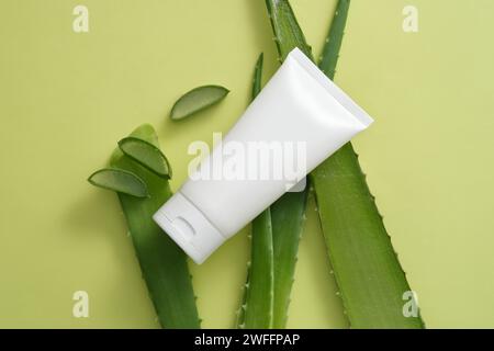 Leeres Etikettenröhrchen in weißer Farbe mit einigen frischen Aloe Vera-Scheiben und -Blättern. Aloe Vera (Aloe barbadensis miller) enthält Polysaccharide und Stockfoto