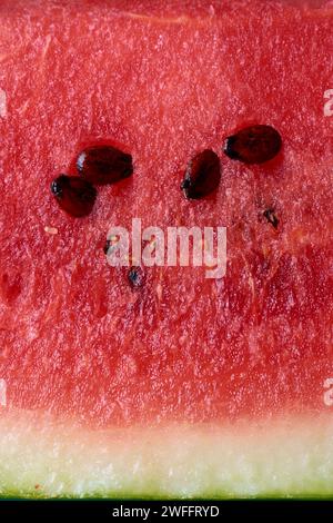 Abstrakt der geschnittenen Wassermelonenoberfläche, heller roter Ton frische saftige Wassermelone mit schwarzem Samen Hintergrund im Vollrahmen, Tapete oder Hintergrund Stockfoto