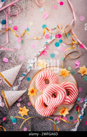 Donuts für Karneval und Party. Krapfen oder Donuts mit Streamer und Konfetti. Buntes Karneval- oder Geburtstagsbild Stockfoto