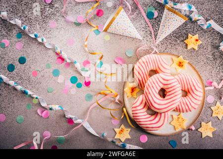 Donuts für Karneval und Party. Krapfen oder Donuts mit Streamer und Konfetti. Buntes Karneval- oder Geburtstagsbild Stockfoto