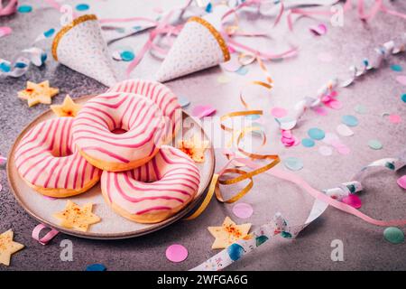 Donuts für Karneval und Party. Krapfen oder Donuts mit Streamer und Konfetti. Buntes Karneval- oder Geburtstagsbild Stockfoto