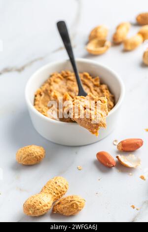 Eine Schüssel mit hausgemachter knuspriger Erdnussbutter und Haufen Nüssen Stockfoto