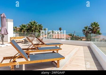 Eine Reihe von Sonnenliegen mit Meerblick auf einer luxuriösen Dachterrasse im mediterranen Apartment Stockfoto