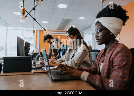 Geschäftskollegen, die Laptops verwenden, während sie am Schreibtisch im Büro arbeiten Stockfoto