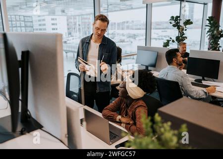 Junger Geschäftsmann, der mit Geschäftsfrau im Amt spricht Stockfoto