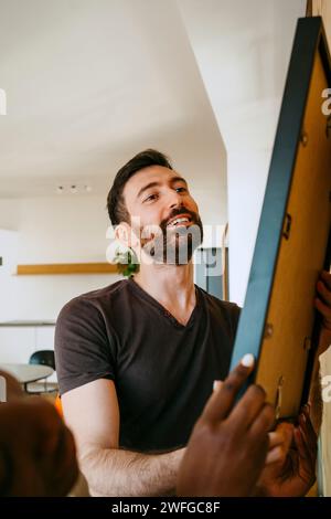 Ein lächelnder Mann hängender Rahmen an der Wand in einem neuen Zuhause Stockfoto