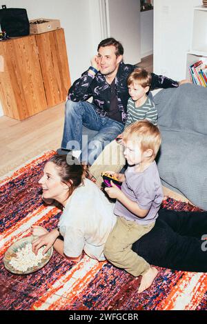 Hochwinkelansicht von Kindern, die Videospiele spielen, während sie mit Eltern zu Hause sitzen Stockfoto
