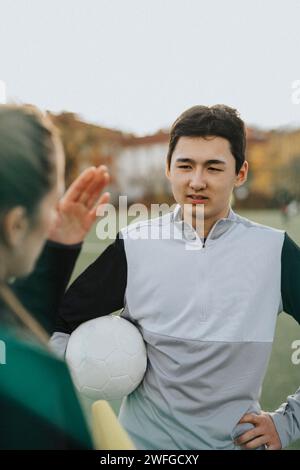 Lehrerin erklärt männlichen Athleten beim Stehen auf dem Sportplatz Stockfoto