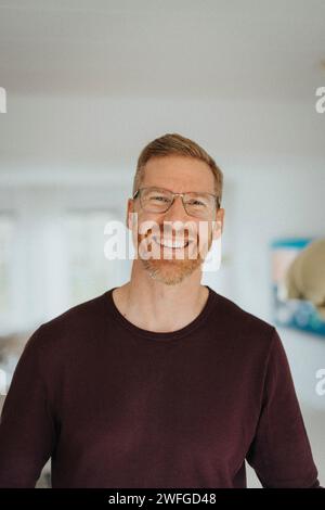 Porträt eines glücklichen reifen Mannes, der im Wohnzimmer eines modernen Hauses steht Stockfoto