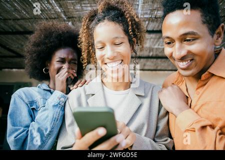 Glückliche Frau, die ihr Handy mit Freunden im Garten teilt Stockfoto