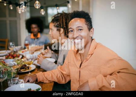 Porträt eines lächelnden Mannes, der während der Dinnerparty auf der Terrasse am Esstisch sitzt Stockfoto