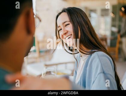 Lächelnde junge Frau, die mit einem Mann auf der Terrasse spricht Stockfoto