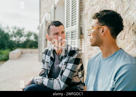 Männliche Freunde reden, während sie im Garten sitzen Stockfoto