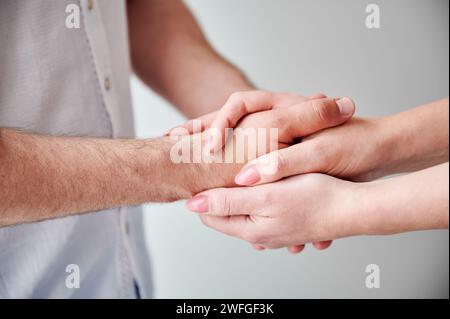 Nahaufnahme von zwei Händen, die eine zarte Berührung ausüben. Hände von Mann und Frau auf weißem neutralen Hintergrund. Der Mann hält die Hand seiner liebenswerten Frau. Konzept von Zuneigung, Unterstützung und gegenseitigem Respekt. Stockfoto