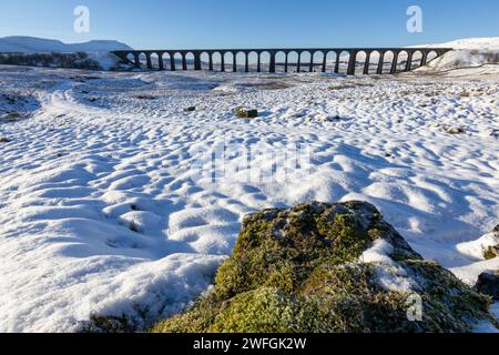 Der Ribblehead Viaduct im Winter in den Yorkshire Dales, mit viel Schnee auf dem Boden und dramatischer Bergkulisse. An einem sonnigen Tag aufgenommen. Stockfoto