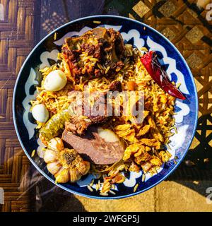 Blick von oben auf einen Teller mit usbekischem orientalischem Pilaf mit Lammstücken, Pferdefleisch, Wachtelreis und Hühnerei. Traditionelle zentralasiatische Küche. Stockfoto