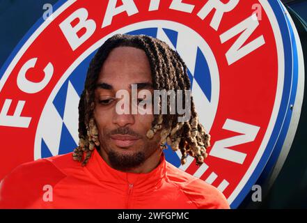 München, Deutschland 31. Januar 2024: Fussball, Herren, Saison 2023/2024, FC Bayern München ! Achtung Fotomontage! Hier im Bild Sacha Boey (FC Bayern München) Kopf, Oberkörper, im Hintergrund das Logo des Vereins, Symbolbild Stockfoto