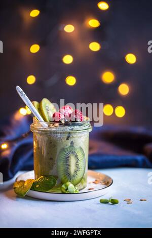 Nahaufnahme eines gesunden veganen Urlaubs-Smoothies mit Kiwi-Früchten und Beeren serviert in Glasgefäßen mit wunderschönem Bokeh im Hintergrund Stockfoto