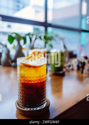 Ein Glas Hummelcocktail mit Eis. Doppelter Espresso mit Orangensaft und Karamellsirup mit Orangensaft und Orangenscheiben auf dem Glas. Frisch und Stockfoto
