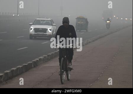 Neu-Delhi, Delhi, Indien. Januar 31, 2024. Ein Mann fährt am 31. Januar 2024 im dichten Nebel in Neu-Delhi, Indien, mit dem Fahrrad auf einer Autobahn (Foto: © Kabir Jhangiani/ZUMA Press Wire). Nicht für kommerzielle ZWECKE! Stockfoto