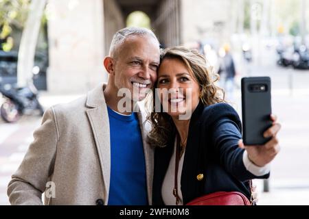 Fröhliches, gutaussehendes Paar, das Spaß hat, zusammen ein Selfie auf der Straße zu machen. Liebevoller älterer Ehemann und Ehefrau, die während eines Fotos machen Stockfoto