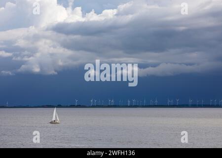 Segelboot auf der Nordsee vor Windturbinen im Sumpfgebiet, Deutschland, Niedersachsen, Ostfriesland, Norddeich Stockfoto