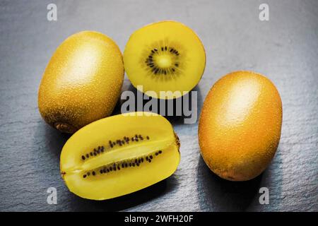 kiwifrucht, chinesische Stachelbeere (Actinidia deliciosa), Kiwis auf schwarzem Hintergrund, zwei Hälften Stockfoto