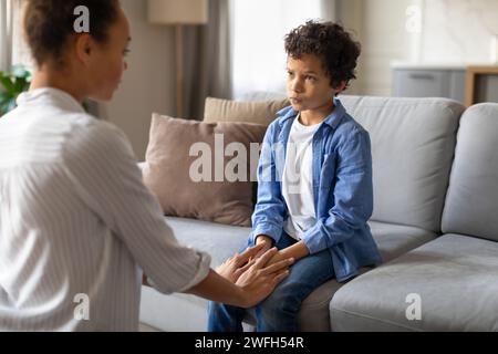 Schwarze Mutter und Sohn im ernsthaften Gespräch auf dem Sofa zu Hause Stockfoto