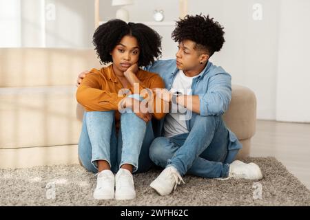 Eine junge Frau wirkt beunruhigt und besinnlich, während sie auf dem Boden sitzt Stockfoto