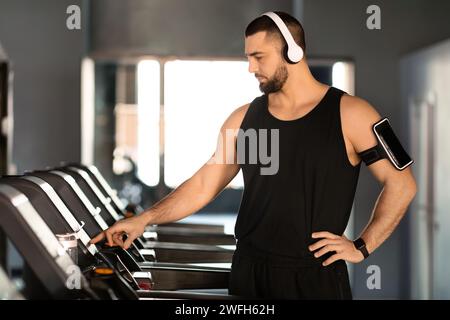 Fitnessstudio-Training. Porträt Eines Gutaussehenden Männlichen Athleten In Kopfhörern, Die Auf Dem Laufband Trainieren Stockfoto