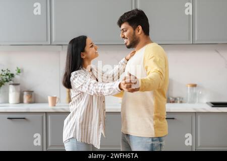 Glückliches junges Ostpaar, das in der Küche tanzt Stockfoto