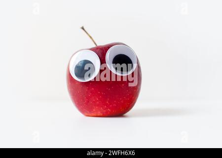 Roter Apfel mit Augen auf weißem Hintergrund Stockfoto