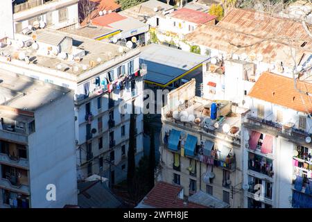 Hochwinkelblick auf typische Apartmenthäuser mit Wäscherei auf Balkonen und Satellitenschüsseln auf den Dächern in Algier, Algerien. Stockfoto