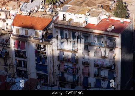 Hochwinkelblick auf typische Apartmenthäuser mit Wäscherei auf Balkonen und Satellitenschüsseln auf den Dächern in Algier, Algerien. Stockfoto