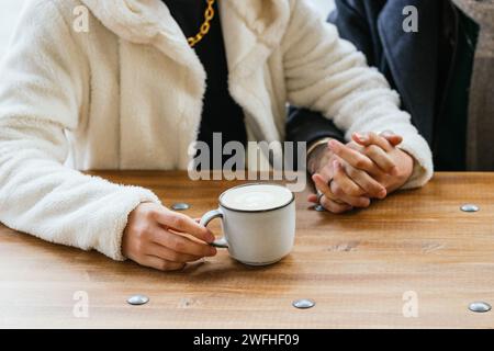 Nahaufnahme eines männlichen Paares, das Hände hält, während er Kaffee in einem Café trinkt. Stockfoto