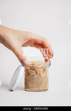 Die Hand einer Frau hält ein Glas Körperpeeling Stockfoto