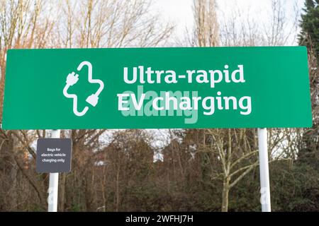 Nahaufnahme eines grün-weißen Schilds mit einer ultraschnellen Ladestation für Elektrofahrzeuge auf einem Parkplatz in Sainsbury's in Großbritannien. Stockfoto