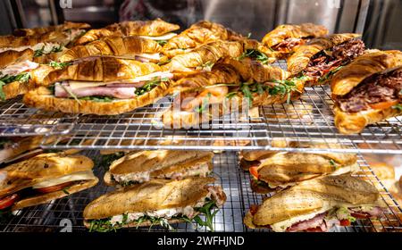 Verschiedene frisch zubereitete Croissant- und Focaccia-Sandwiches mit köstlichen Füllungen in einem Feinkostgeschäft. Stockfoto