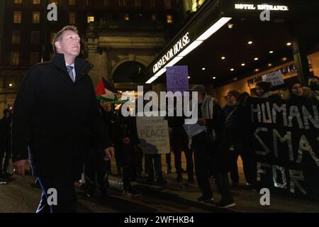 London, Großbritannien. 30. Januar 2024. Ein Gast, der im JW Marriott Grosvenor House Hotel zum jährlichen Dinner der ADS ankommt, stößt auf einen Protest von Aktivisten gegen den Waffenhandel. Das ADS Annual Dinner bringt Vertreter von Unternehmen aus der Luft- und Raumfahrt, Verteidigung, Sicherheit und Raumfahrt zusammen. Zu den Sponsoren der Veranstaltung gehört BAE Systems, das Komponenten für F-35-Kampfflugzeuge liefert, die Israel während seiner Invasion in Gaza eingesetzt hat. Quelle: Mark Kerrison/Alamy Live News Stockfoto