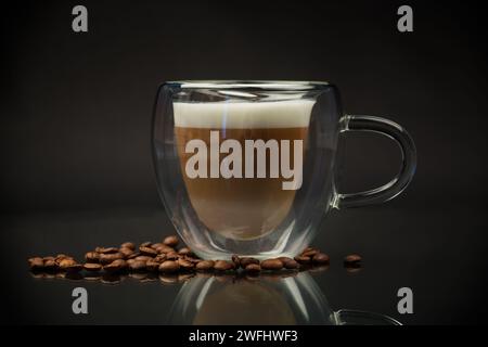 Heißer Kaffee mit Milch in Glasbecher isoliert auf schwarzem Hintergrund Stockfoto