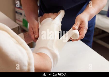 Der Arzt legt ein Pflaster auf den Arm eines Patienten im Krankenhaus mit einem gebrochenen Arm Stockfoto