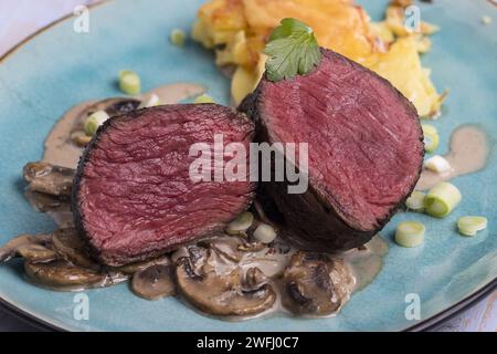 Schneiden Sie Steak und Kartoffelgratin auf Einen Teller Stockfoto