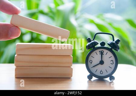 Wecker auf dem Tisch, der auf 8:00 Uhr zeigt, mit Holzblöcken und anpassbarem Platz für Text. Zeitkonzept Stockfoto