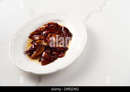 Karamellisierte Äpfel mit Gewürzen in weißer Platte. Kann für Kuchen oder Crumble gefüllt und über französischen Toasts oder Pfannkuchen serviert werden. Erstklassiges Lebensmittelfoto Stockfoto