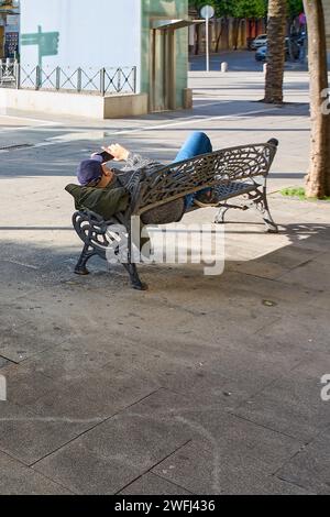 Unerkennbarer Erwachsener, der auf einer Parkbank ruht und auf sein Handy schaut Stockfoto