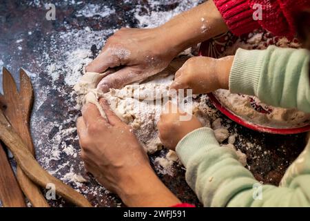 Zwei Personen kooperieren zusammen, um Brot auf einem Tisch zu machen, umgeben von verschiedenen Utensilien Stockfoto