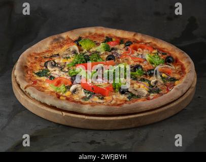 Eine Pizza mit Schinken, Mozzarella, schwarzen Oliven, Pilzen, rotem Pfeffer und Brokkoli Stockfoto