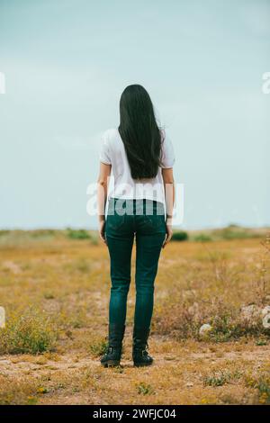 Rückansicht der jungen Frau, die auf dem Feld steht Stockfoto