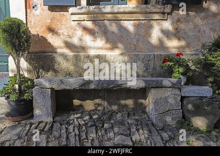 Bild einer Steinbank vor einem alten Gebäude in einem historischen Kraot-Dorf während des Tages Stockfoto