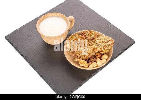 Mehrere Thaler-Kekse mit Nüssen auf einem Schieferstein mit einer Tasse Sauerrahm, Nahaufnahme, isoliert auf weißem Hintergrund. Stockfoto